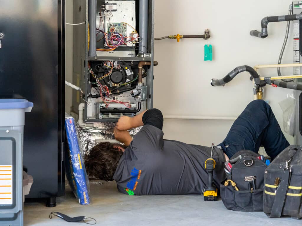 Employee On The Ground Repairing A Furnace Unit