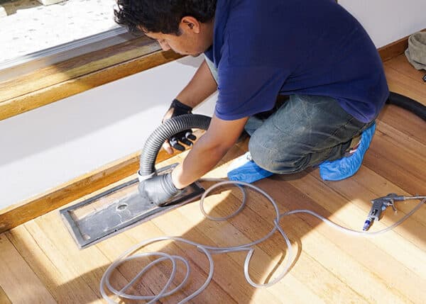 Image Of Man Cleaning Ductwork From A Floor Vent
