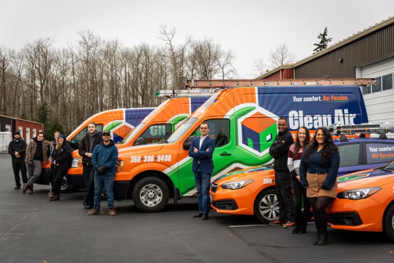 a group of people standing in front of Clean Air's orange and green vans